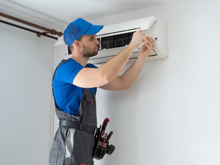 Técnico de uniforme trabalhando no painel de um ar-condicionado split